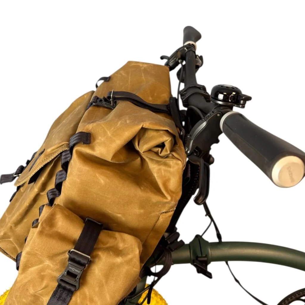 Bromfort in Tan hinter dem Lenker von schräg oben: Rolltop und Fidlock-Schnalle