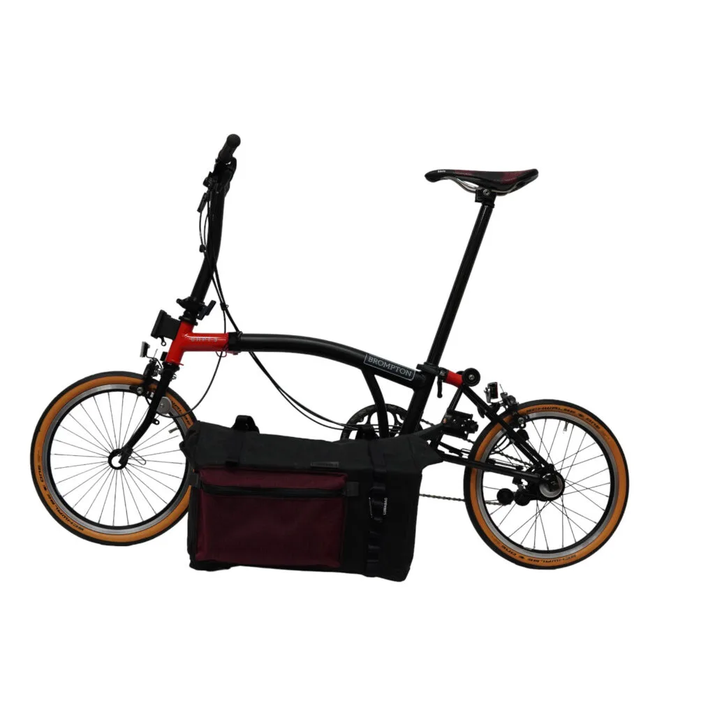 Brompton with folded handlebar, the QUER with its dark red front pocket still mounted on the carrier block