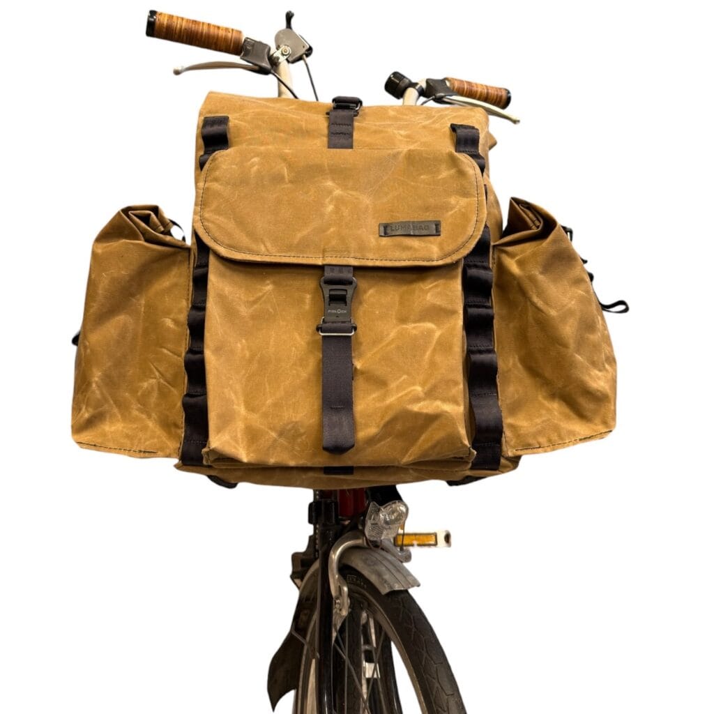 Bromfort in Tan von vorn am Rad: Frontklappe mit LUMABAG-Patch, Fidlock-Verschluss und seitliche Rolltop-Taschen